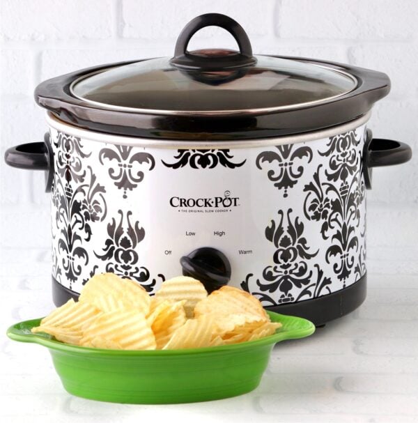 Potato chips in dish in front of slow cooker with cheese dip.
