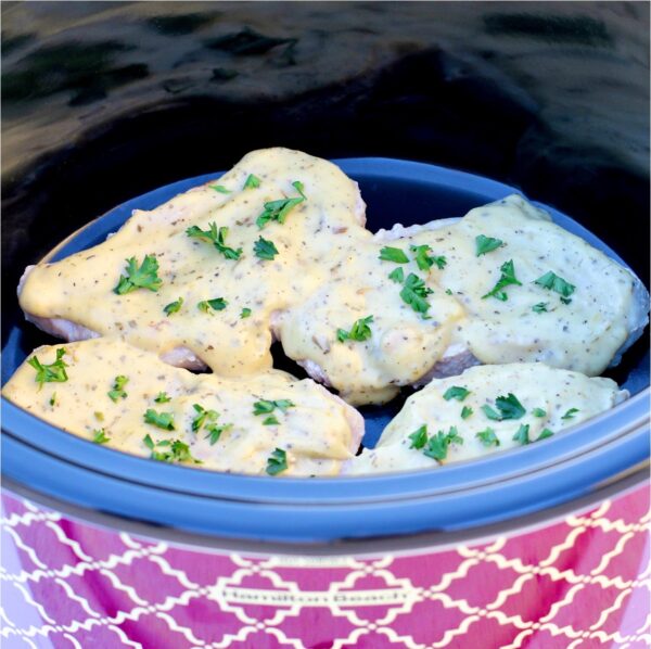 Cooked Italian pork chops with sauce in slow cooker.