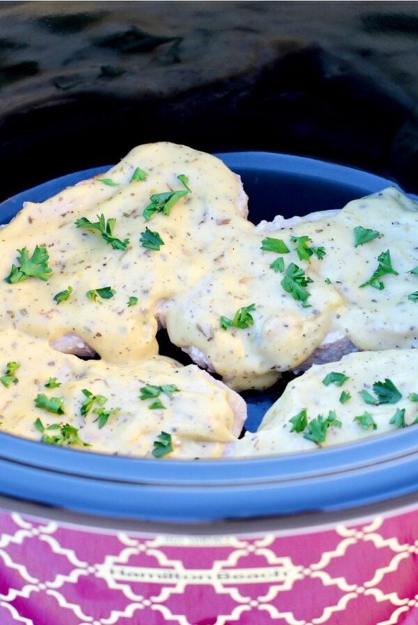 Cooked Italian pork chops with white sauce in crockpot.