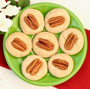 Seven thumbprint pecan cookies on plate.