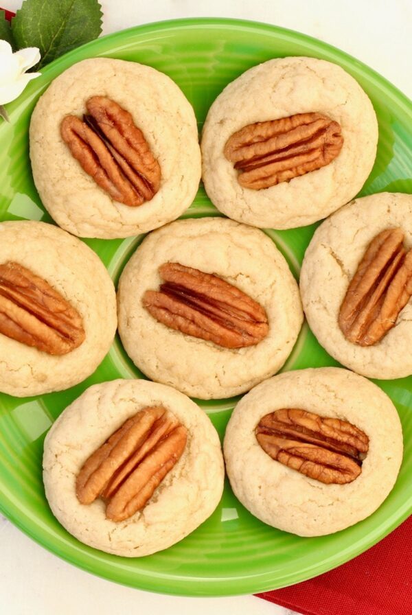 Seven thumbprint pecan cookies on plate.