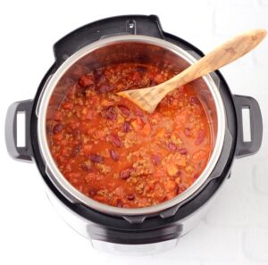 Chili in an Instant Pot with a wooden spoon.