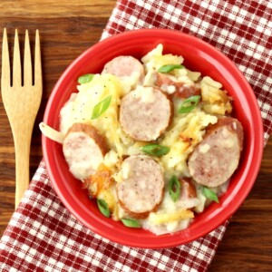 Sausage and potatoes in a red bowl.