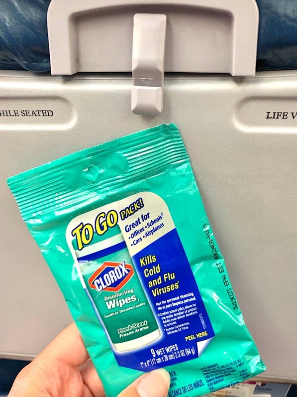 Sanitizing wipes in front of airplane seat tray table.