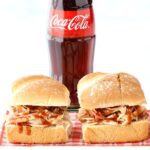 Barbecue chicken sandwiches with a bottle of Coke.
