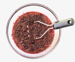 Masher in a bowl of mashed blackberries.