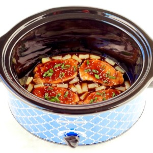 Cooked pork chops in crockpot with teriyaki sauce and pineapples.