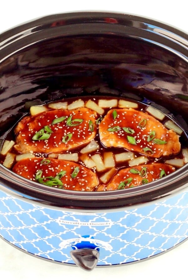 Cooked pork chops in crockpot with teriyaki sauce and pineapples.
