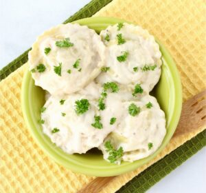 Green bowl of Alfredo Ravioli.