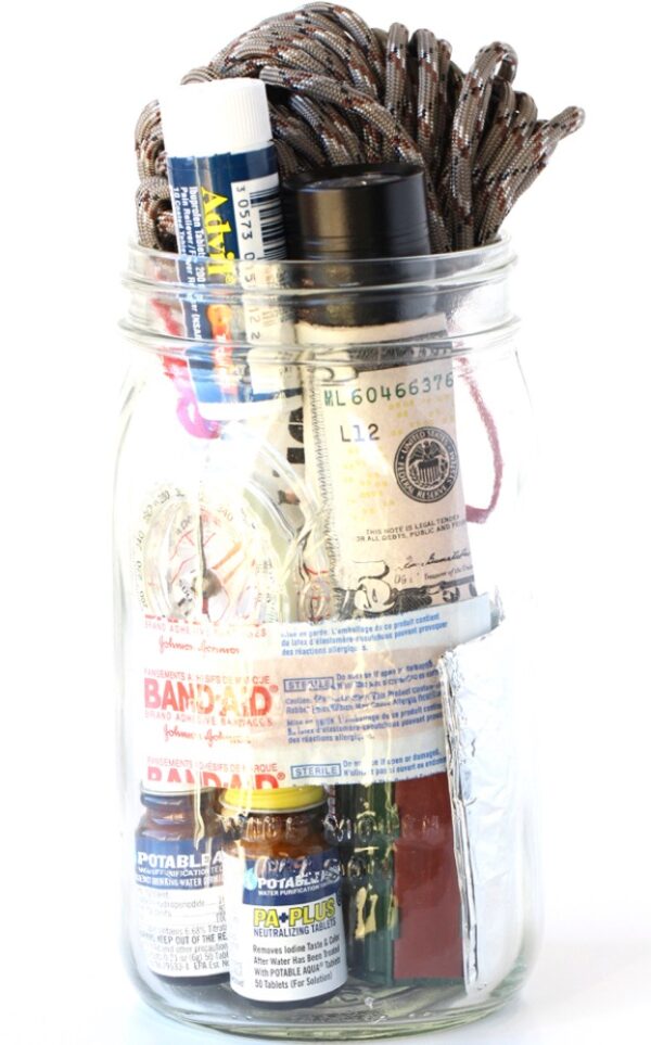 Mason jar filled with survival essentials including paracord, cash, and bandaids.