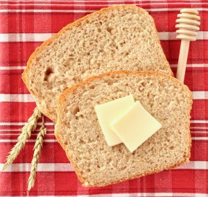 Slices of honey wheat sandwich bread with butter.
