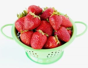 Green colander of strawberries.