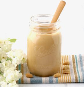 Wooden spoon in a jar of peanut butter.