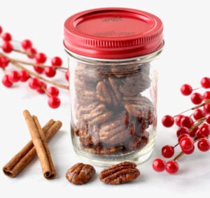 Candied cinnamon sugar pecans in mason jar with red lid.