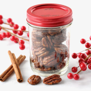 Candied cinnamon sugar pecans in mason jar with red lid.