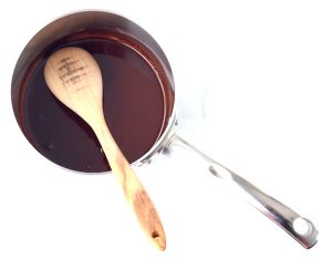 Wooden spoon in a pan with a chocolate syrup.
