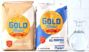 Bags of whole wheat and all purpose flour with a pitcher of water.