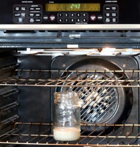 Jar of sourdough starter in an oven.