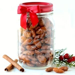 Candied cinnamon sugar coated almonds in mason jar with cinnamon sticks.