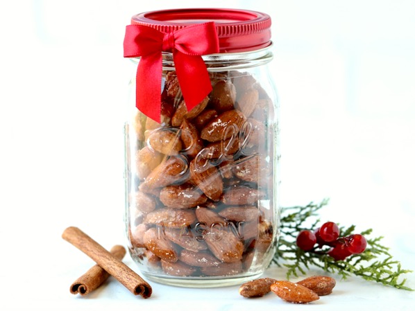 Candied cinnamon sugar coated almonds in mason jar with cinnamon sticks.