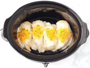 Garlic Chicken topped with cheese in a slow cooker.