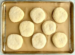 Lined baking sheet with discs of dough.