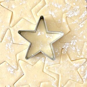 Star cookie cutter cutting out dough.