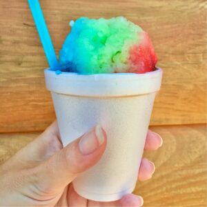 Person holding a snow cone in a cup.