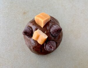 Ball of cookie dough stuck with caramels and chocolate chips.