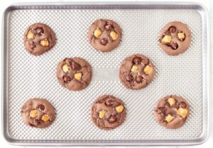 Salted caramel chocolate chip cookies on a baking sheet.