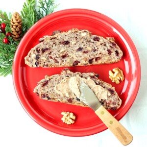 Knife spreading butter on cranberry walnut bread.