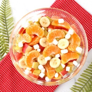 Fruit salad with bananas and marshmallows in a glass bowl.