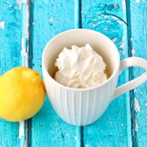 Mug with whipped cream next to a lemon.