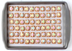 Easter hugs topped with M&Ms on a lined baking sheet.