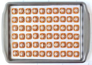Hugs on pretzels on a lined baking sheet.