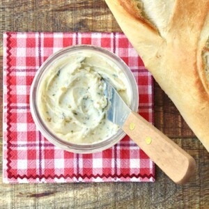 Butter knife in a small bowl of garlic butter.