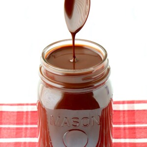 Spoon dripping chocolate syrup into a jar.