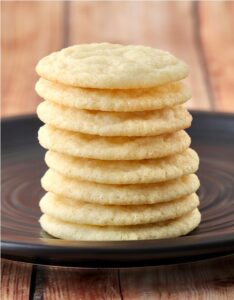 Stack of sugar cookies on a black plate.