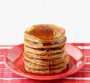 Syrup pouring over a stack of banana oat flour pancakes.