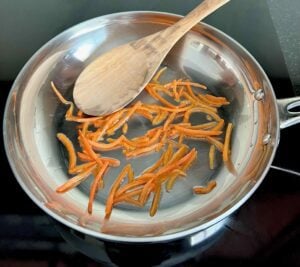 Wooden spoon in a pan of carrots.