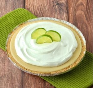 Key lime pie with whip cream and lime slices on top.
