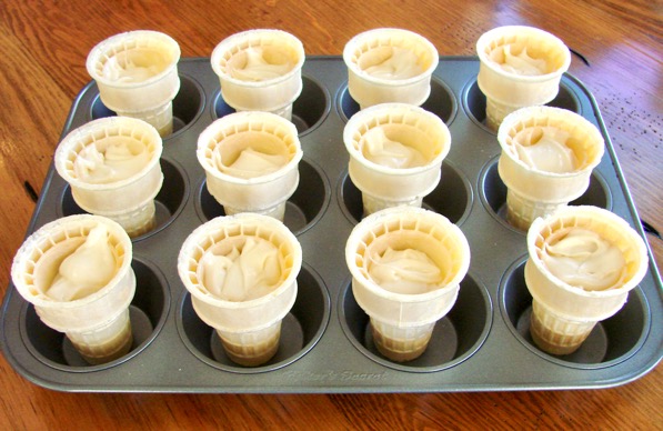 Ice cream cones in cupcake pan with cupcake batter inside.