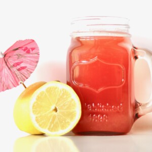 Pineapple Pink Lemonade Party Punch in a jar next to lemons.