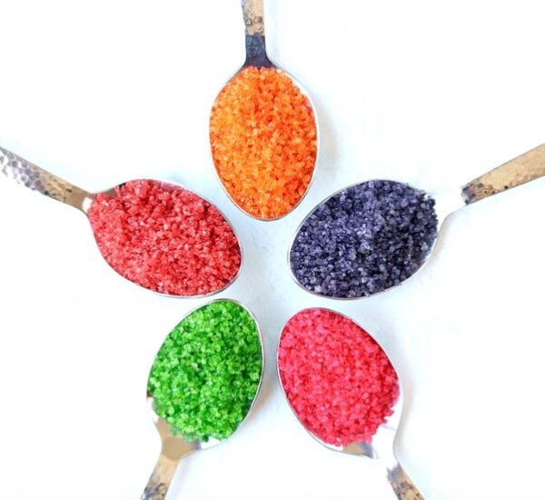 Homemade colored sugar sprinkles on 5 different spoons.