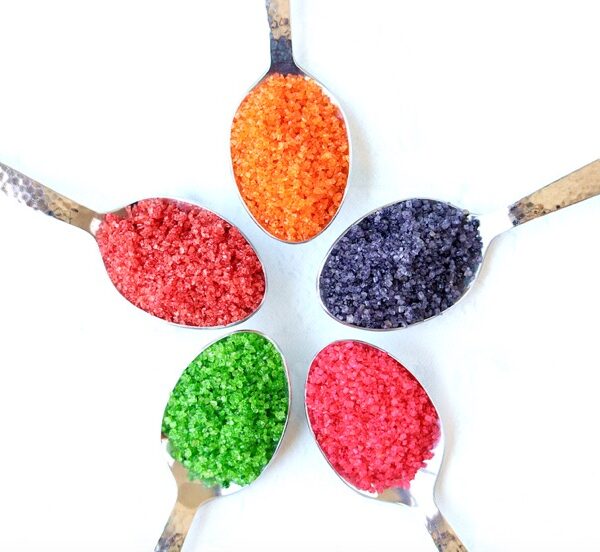 Homemade colored sugar sprinkles on 5 different spoons.