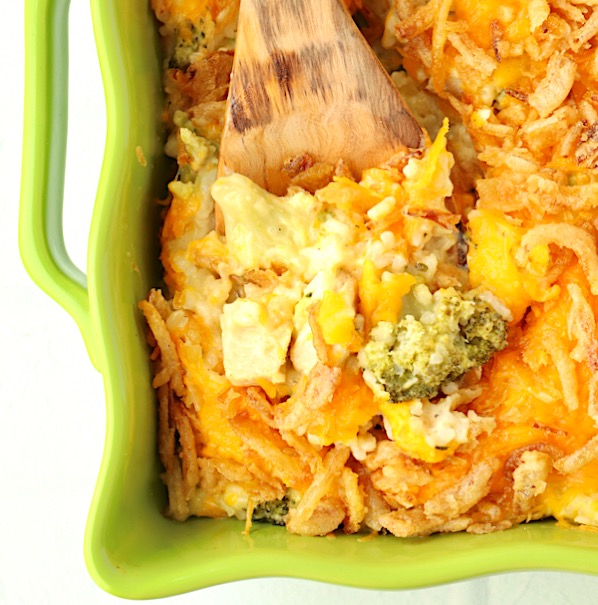 Wooden spoon scooping chicken broccoli rice casserole.