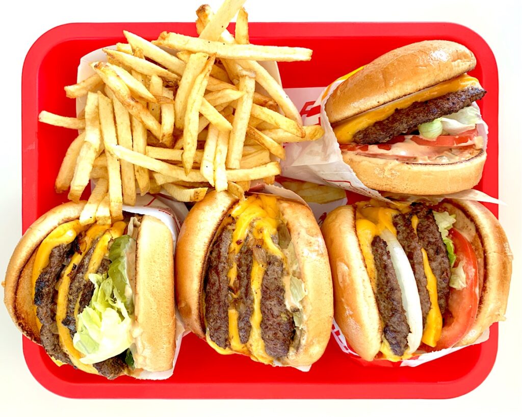 Burgers and French fries on a red tray.