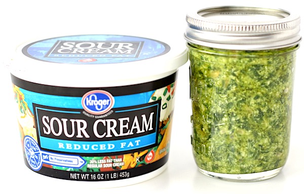 Tub of sour cream and jar of pesto.