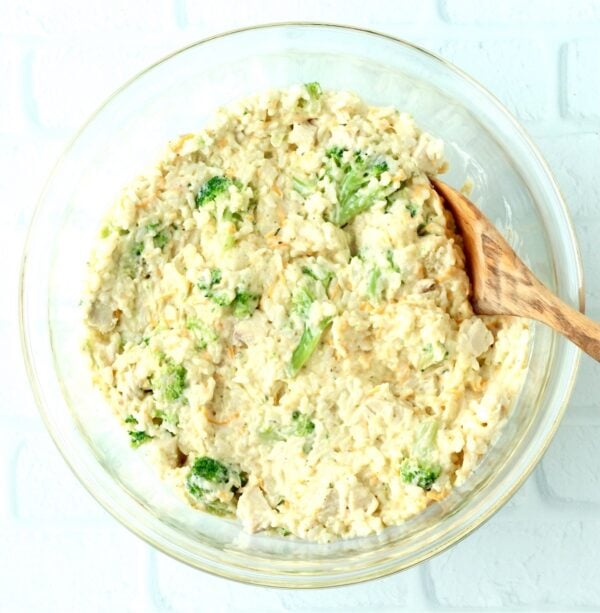 Broccoli casserole ingredients in bowl with wooden spoon.