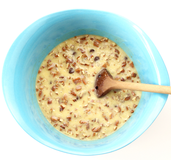 Pecan pie filling in mixing bowl with wooden spoon.